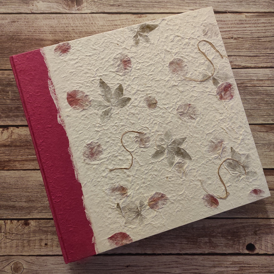 Album fotografico artigianale con copertina a due colori in carta di gelso con petali rosa e foglie verdi abbinata a carta di Gelso tinta unita colore fucsia.
