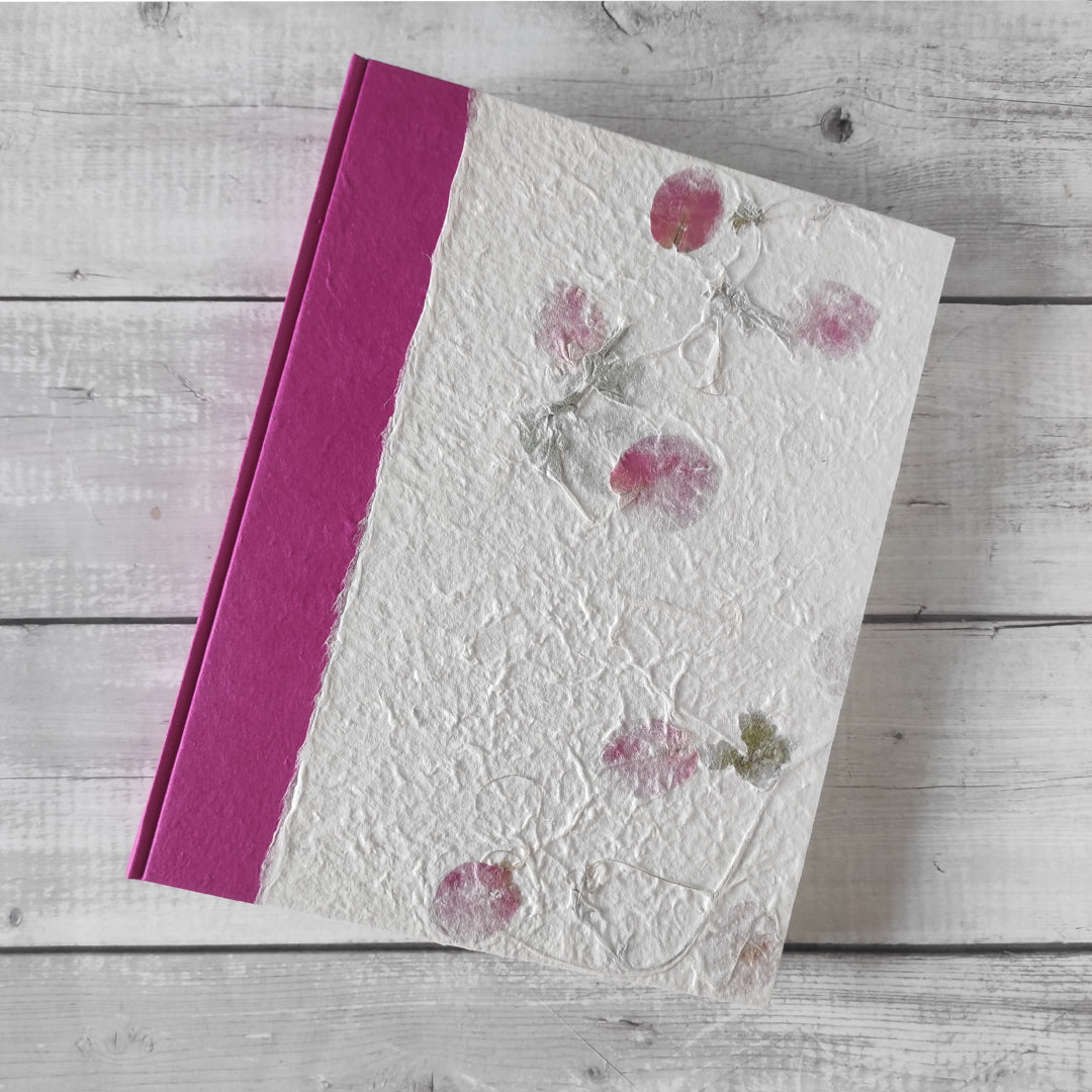 Copertina album fotografico artigianale in carta di gelso inserti botanici rametti con petali rosa e foglie su fondo avorio